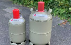 graue 5 kg und 11 kg Flaschengas Gasflaschen nebeneinander mit roten Verschlusskappen
