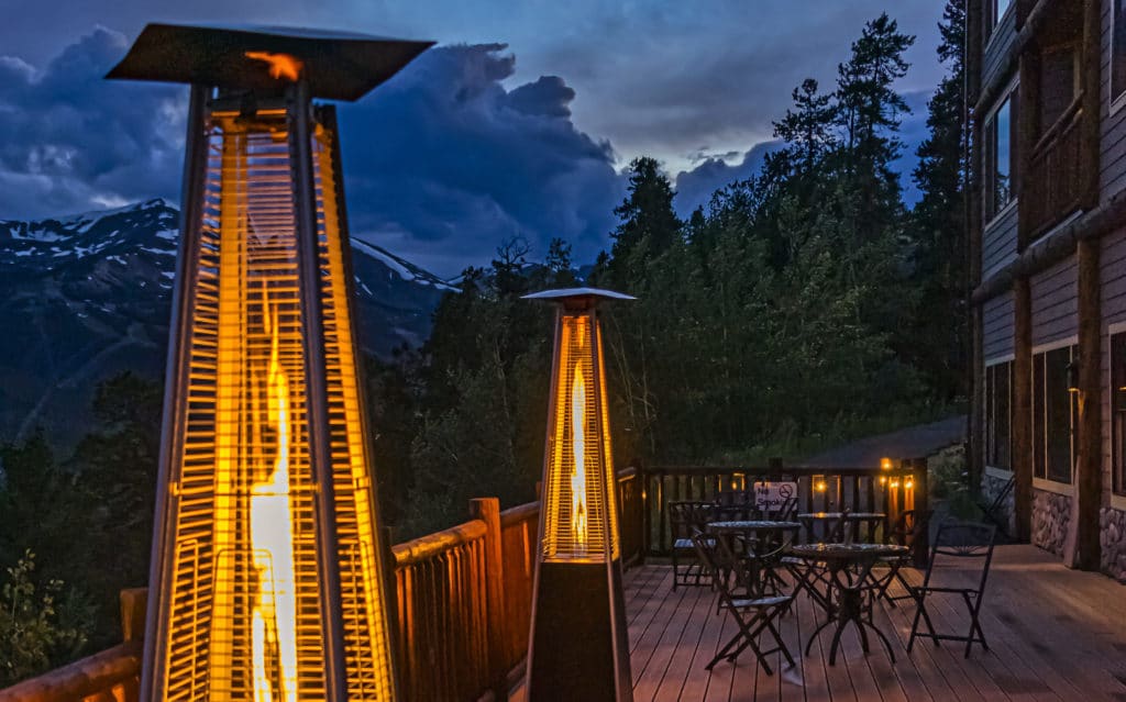 zwei Terrassenheizungen mit Gas stehen auf einer Holzterrasse im Hintergrund Berge