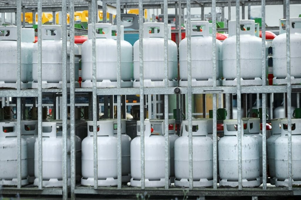 Graue Alu Gasflaschen stehen in Transportkäfigen bei einem Gasflaschenhändler