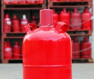 Rote Propangasflasche Pfandgasflasche vor Gasflaschenlager auf einem Betriebshof