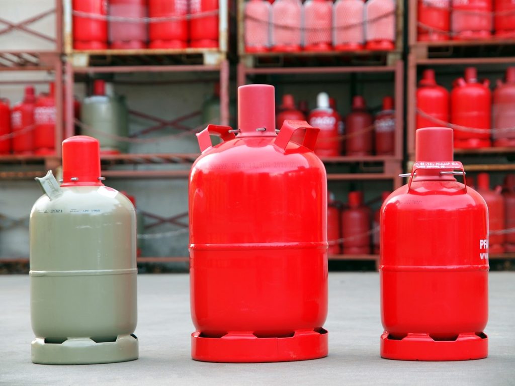 Verschieden Gasflaschengrößen von roten Pfandflaschen und grauen Kauf Gasflaschen im Lager